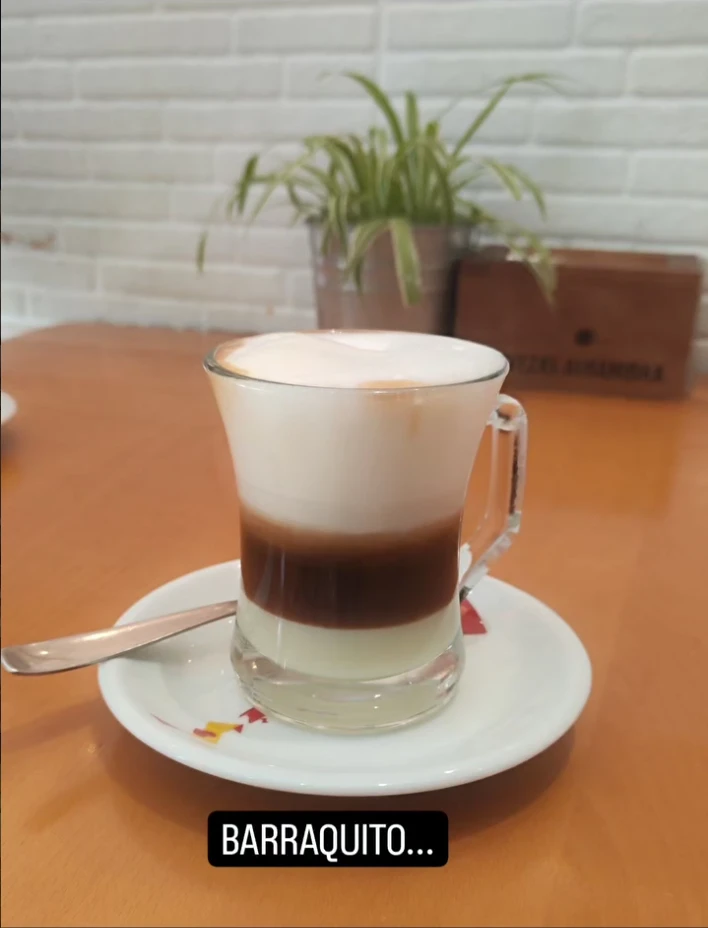 Barraquito servido en una taza de cristal sobre un plato